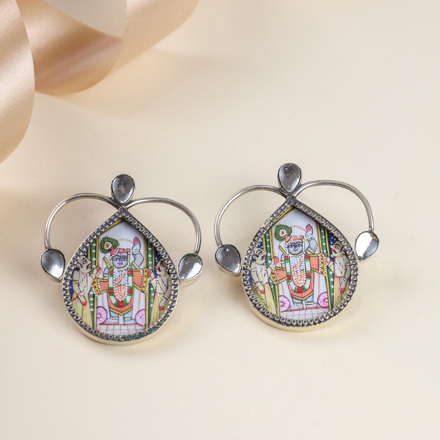 Pair of earrings with intricate designs on a beige background