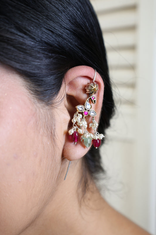 Close-up of an ear wearing a decorative earring with gemstones.