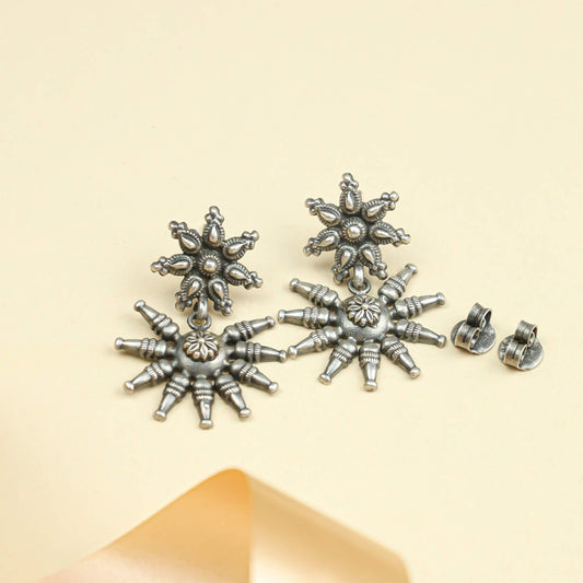 Pair of silver star-shaped earrings on a beige background
