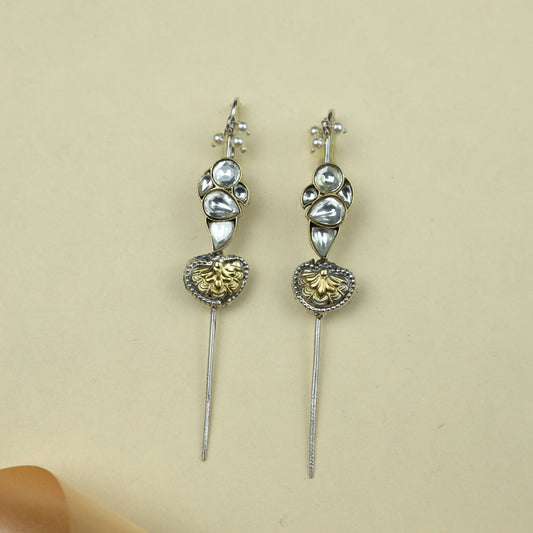 Pair of decorative earpins with gold and silver details on a beige background