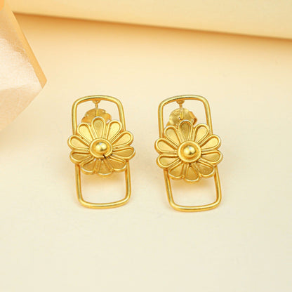 Pair of gold floral earrings on a beige background